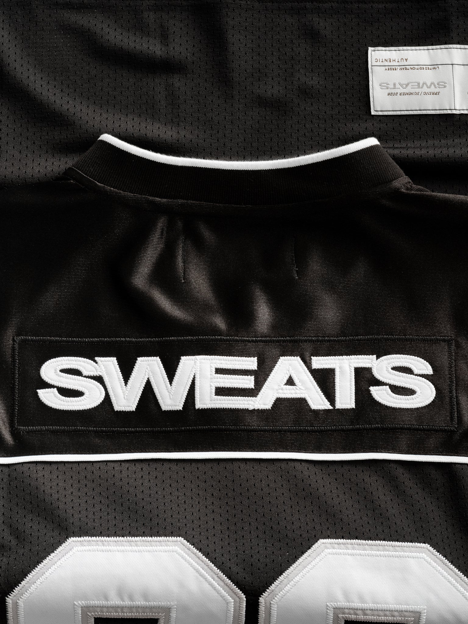 Black Signature Jersey by SWEATS EU displayed flat, showing its sleek design and fabric texture.