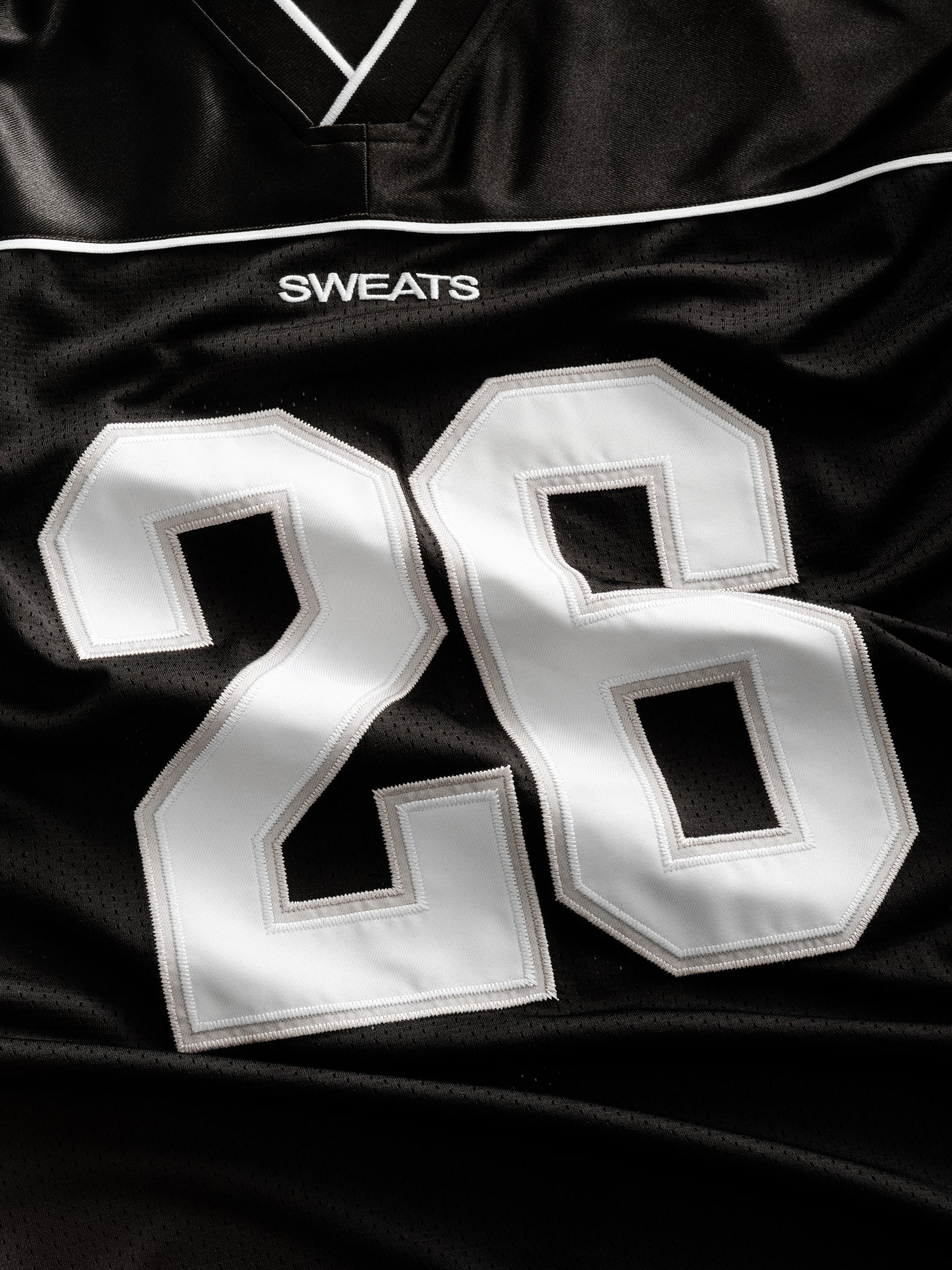 Black SIGNATURE JERSEY by SWEATS EU displayed flat, showing the fabric texture and design details of the sports jersey.