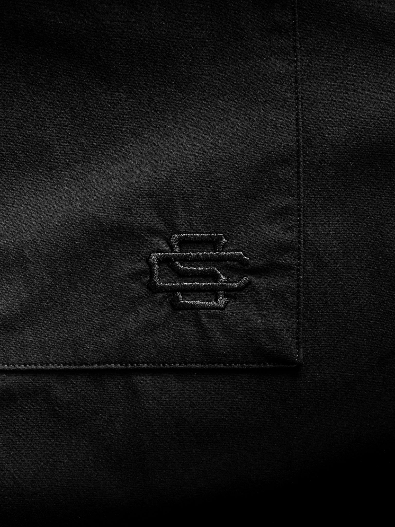 Black Signature Button Up shirt by SWEATS EU laid flat showing collar, buttons, and fabric texture.