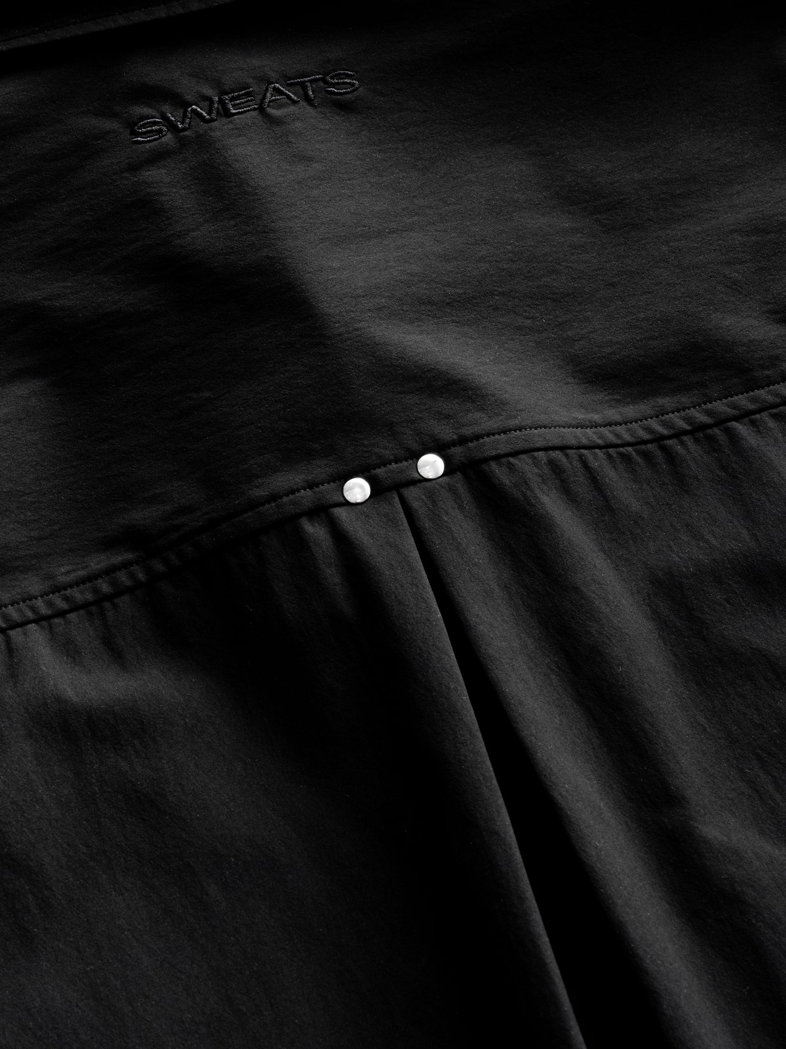 Black Signature Button Up shirt by SWEATS EU, laid flat showing collar, buttons, and sleek fabric detail.