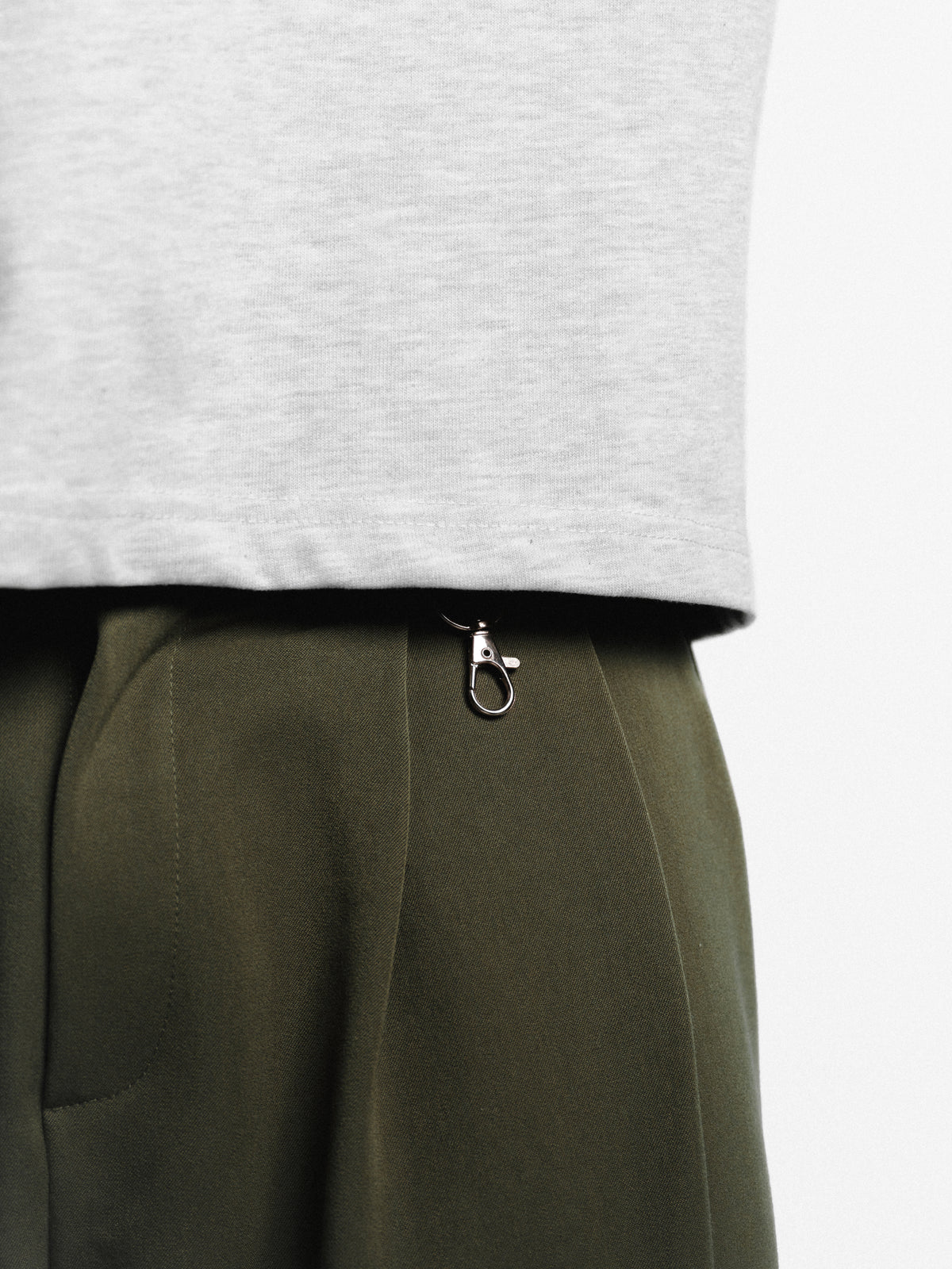 Olive pleated pants by SWEATS EU displayed on a hanger, showcasing the stylish design and fabric texture.