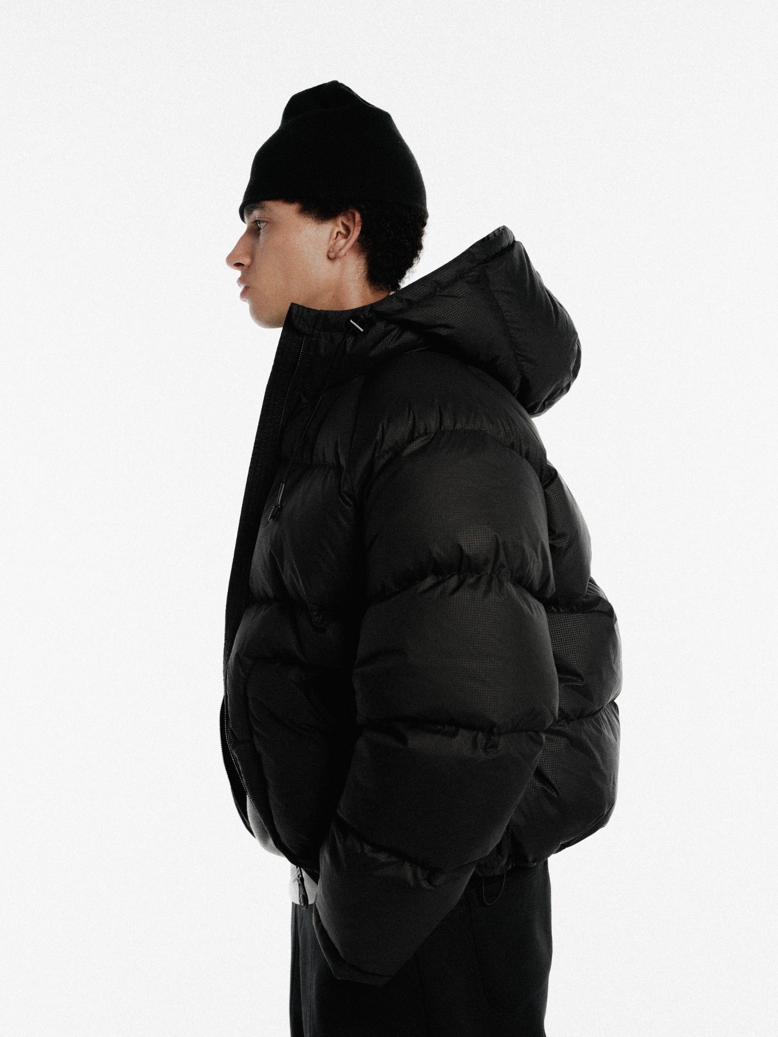 Black hooded puffer jacket by Sweats EU, showcasing its quilted design and cozy hooded style for winter warmth.