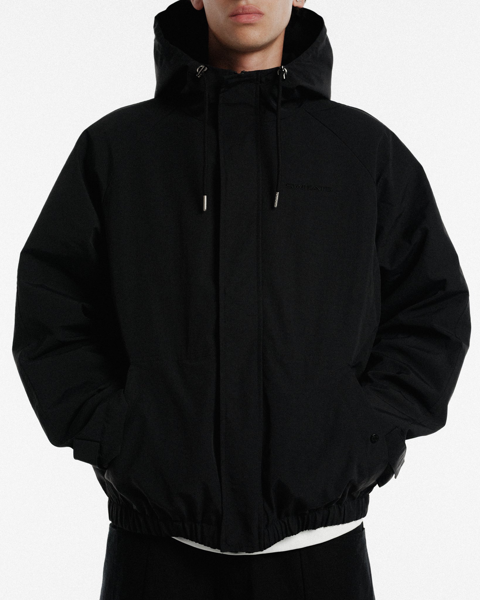 Black ARC jacket by SWEATS EU displayed on a hanger with visible zipper details and sleek winter fashion style.