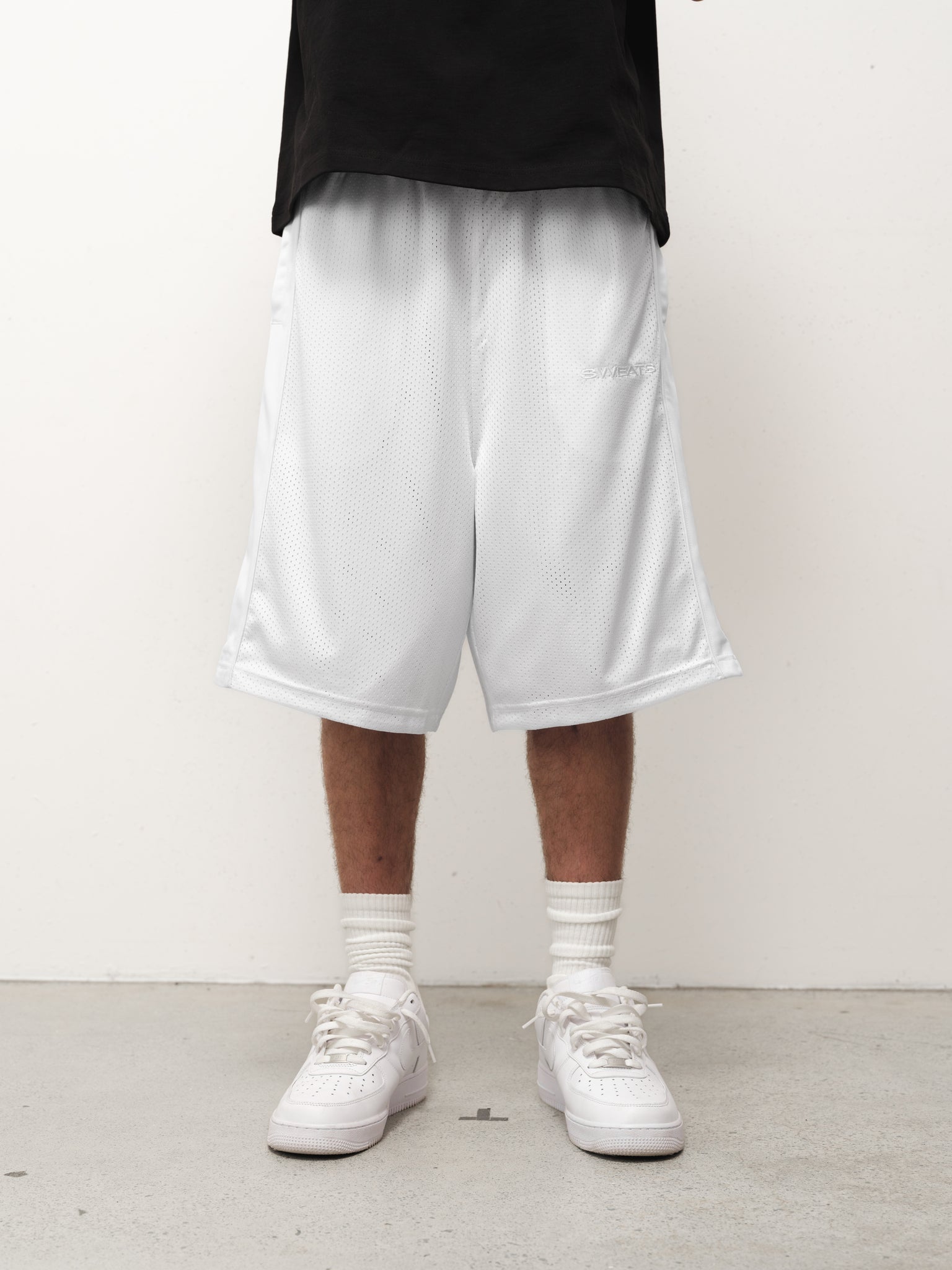 White mesh shorts by SWEATS EU displayed on a flat surface, showcasing breathable fabric and sporty design.