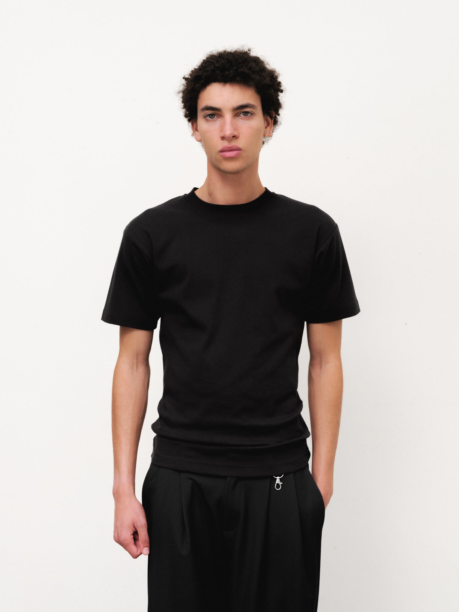 Black fitted T-shirt by SWEATS EU, shown flat on a surface with a close-up of the fabric and neckline.
