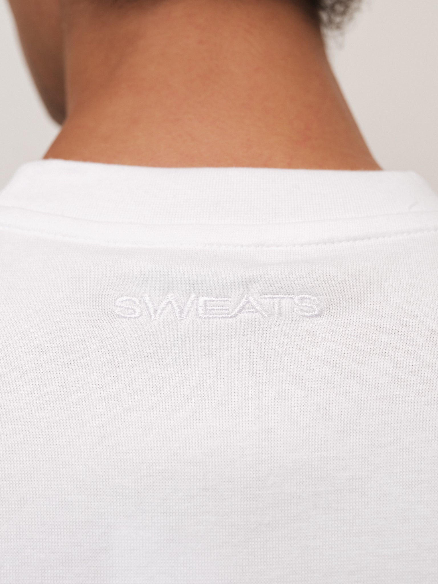 White fitted T-shirt from SWEATS EU displayed on a mannequin, showcasing a casual, slim-fit design ideal for everyday wear.
