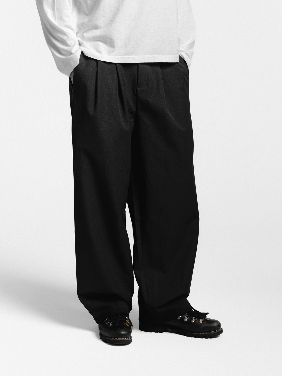 Black pleated pants by Sweats EU, stylish and comfortable, shown on a model with a focus on the tailored pleats and fit.