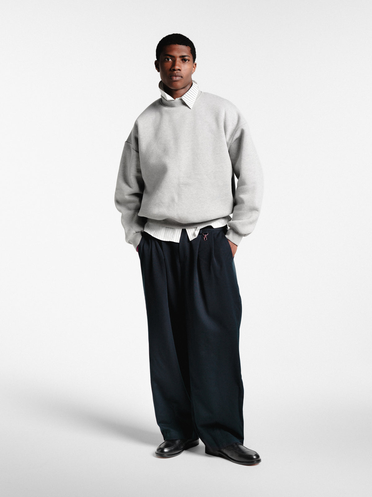 Navy pleated pants by Sweats EU displayed on a hanger, showcasing the tailored fit and fabric texture.