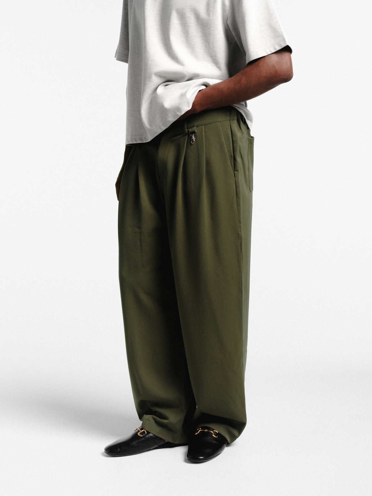 Olive pleated pants by SWEATS EU, featuring a relaxed fit and tailored design, displayed on a neutral background.