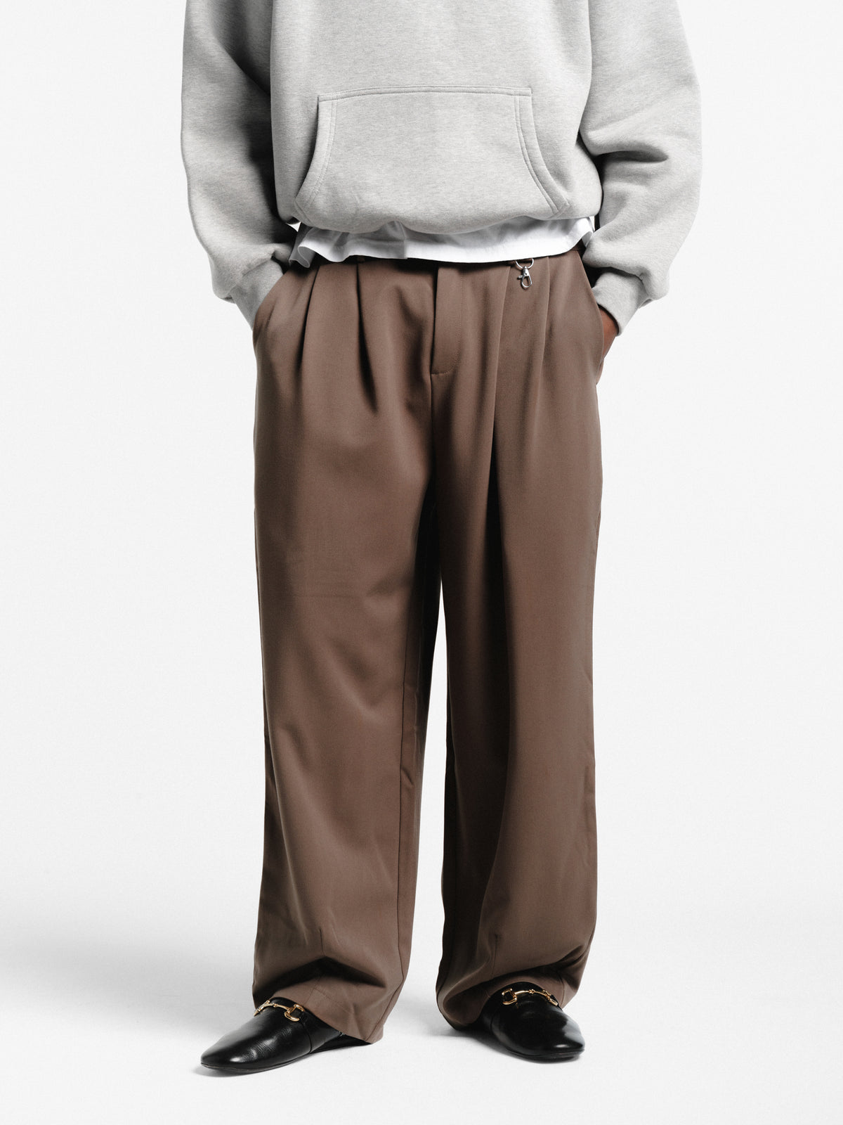 Brown pleated pants from Sweats EU, featuring a tailored fit and classic design, shown on a neutral background.