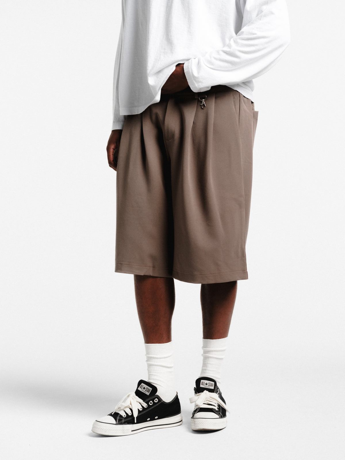 Brown pleated shorts from Sweats EU, displayed flat with a focus on the fabric texture and pleated design.