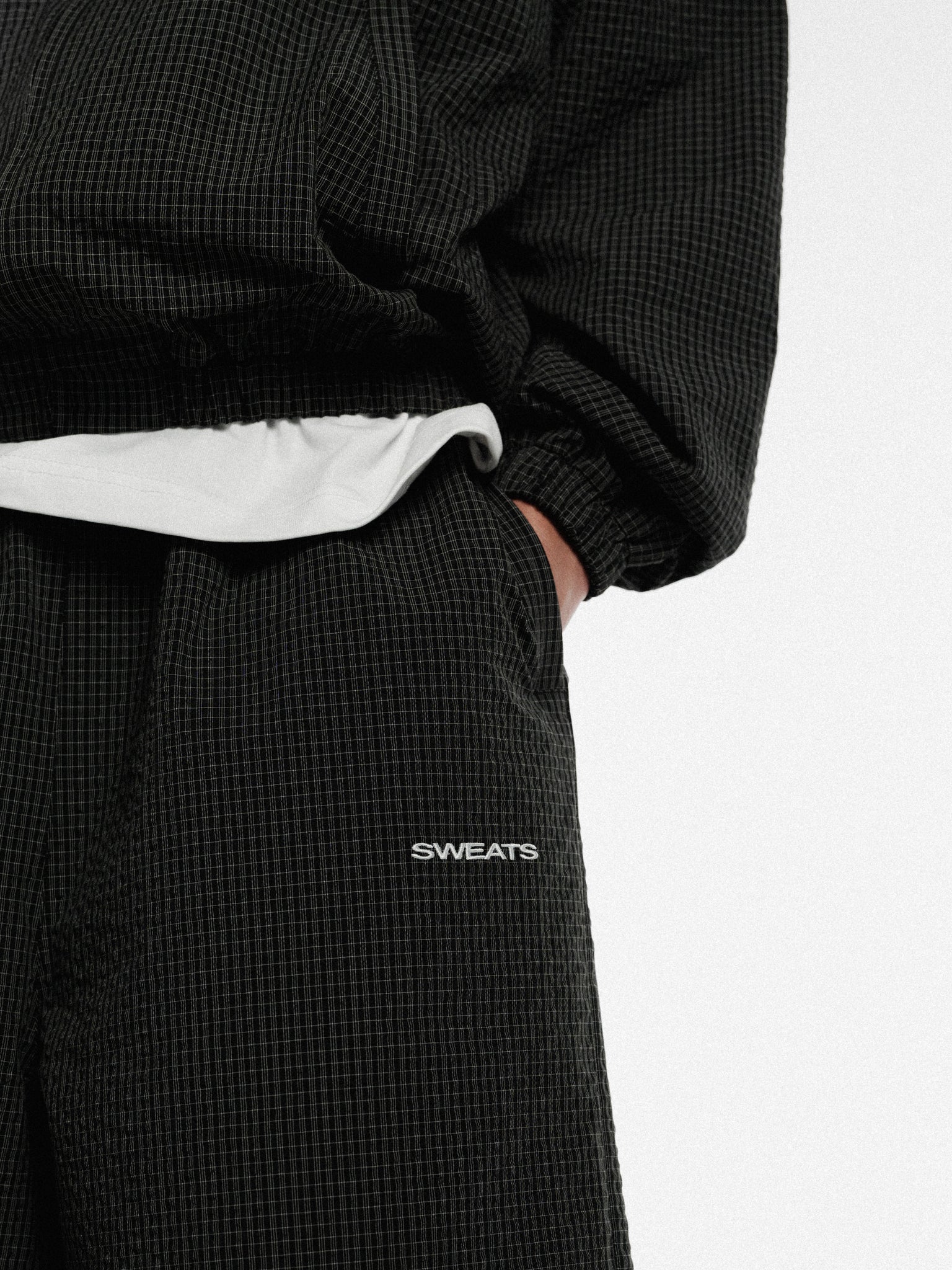 Black and white checkered track shorts from SWEATS EU, featuring a sporty design and comfortable fit.