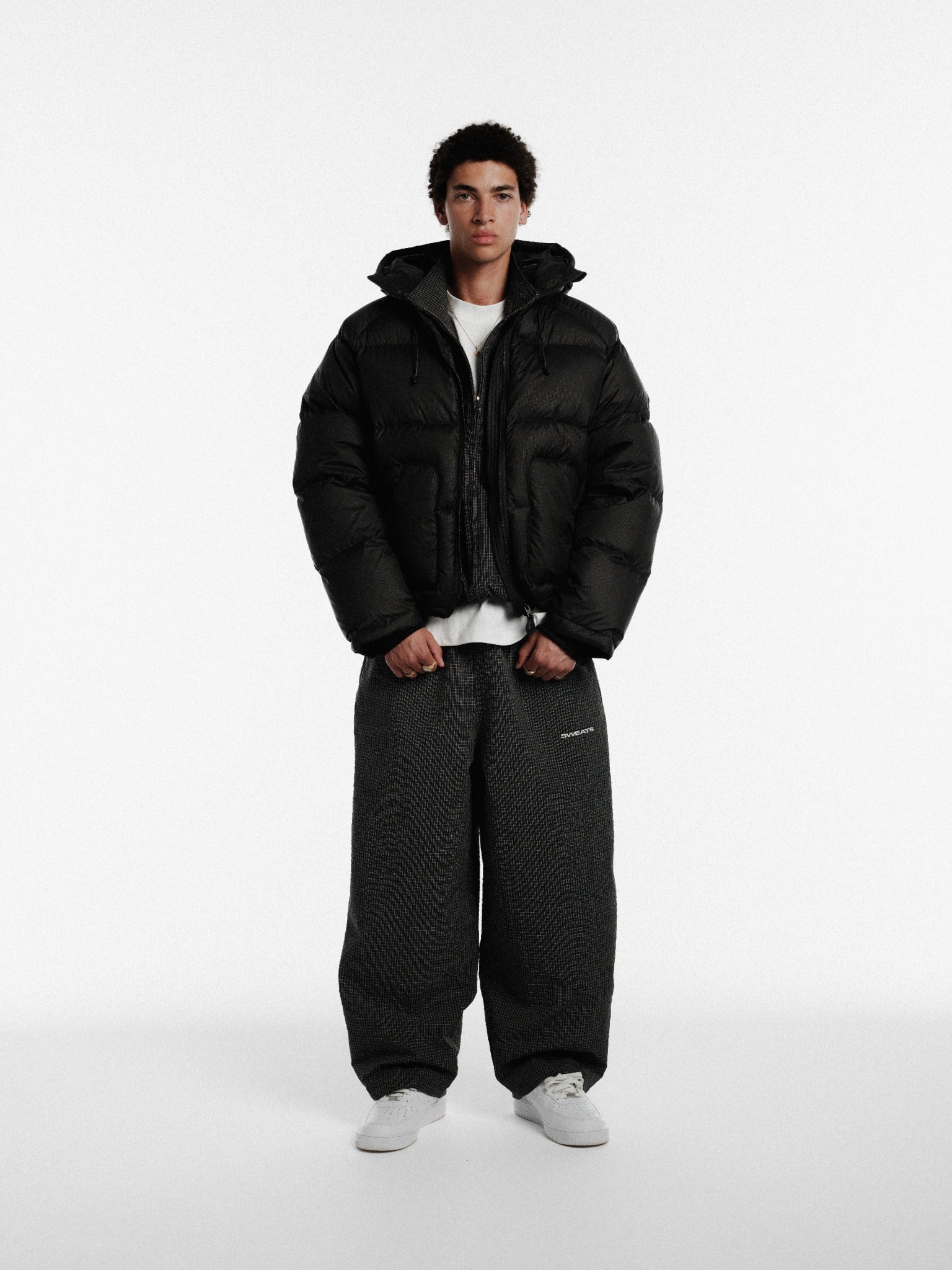 Black hooded puffer jacket from SWEATS EU, featuring a padded design and a cozy hood for winter warmth.