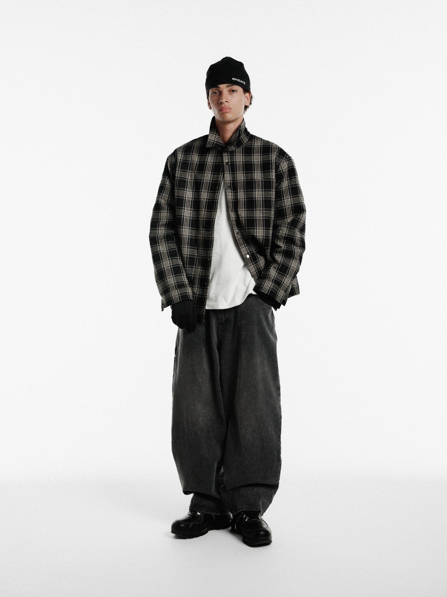 Black flannel jacket from SWEATS EU with a classic plaid pattern and button closure, displayed on a hanger.