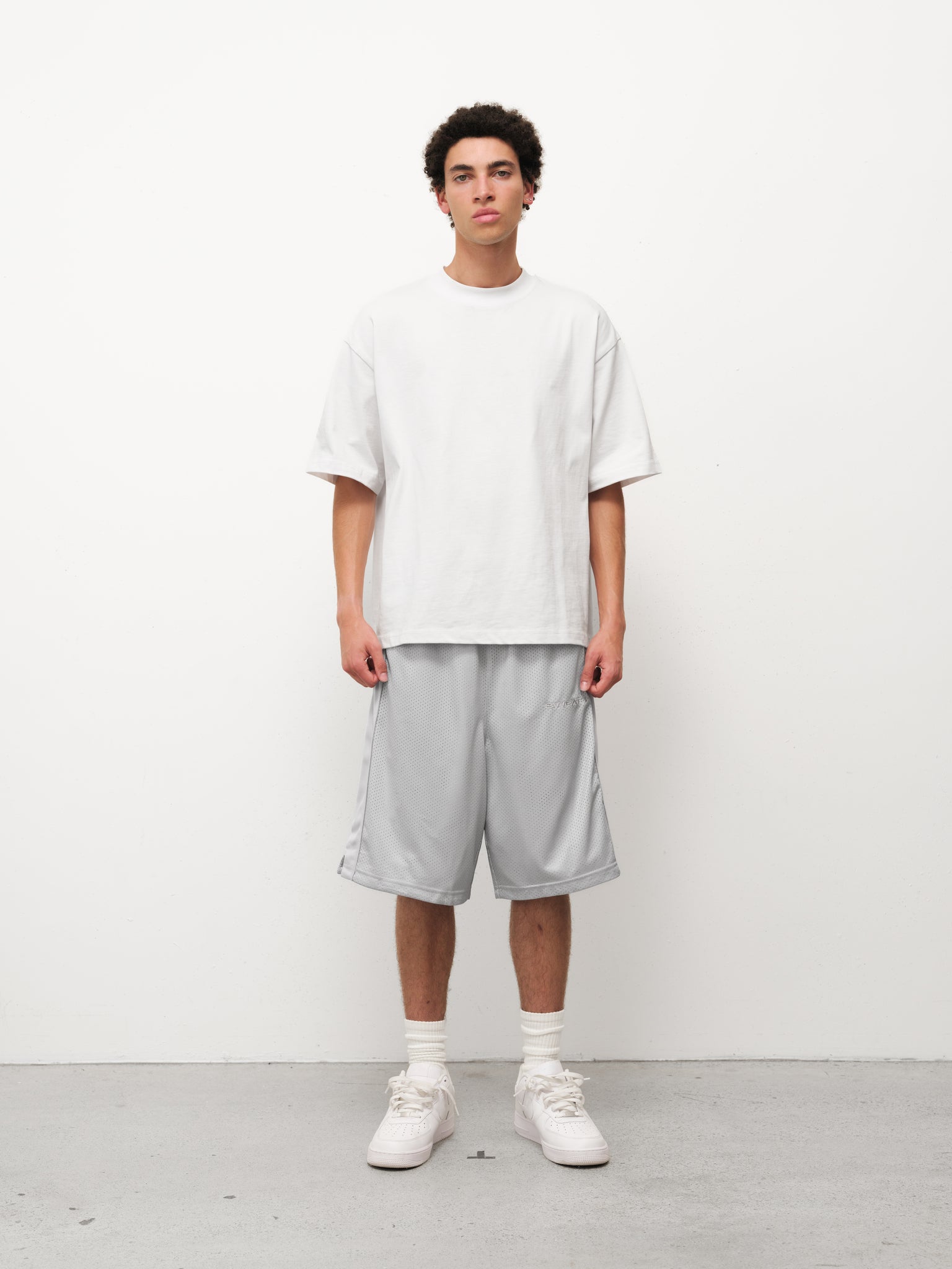 Grey mesh shorts by Sweats EU displayed on a model in a casual setting, showcasing breathable fabric and relaxed fit.