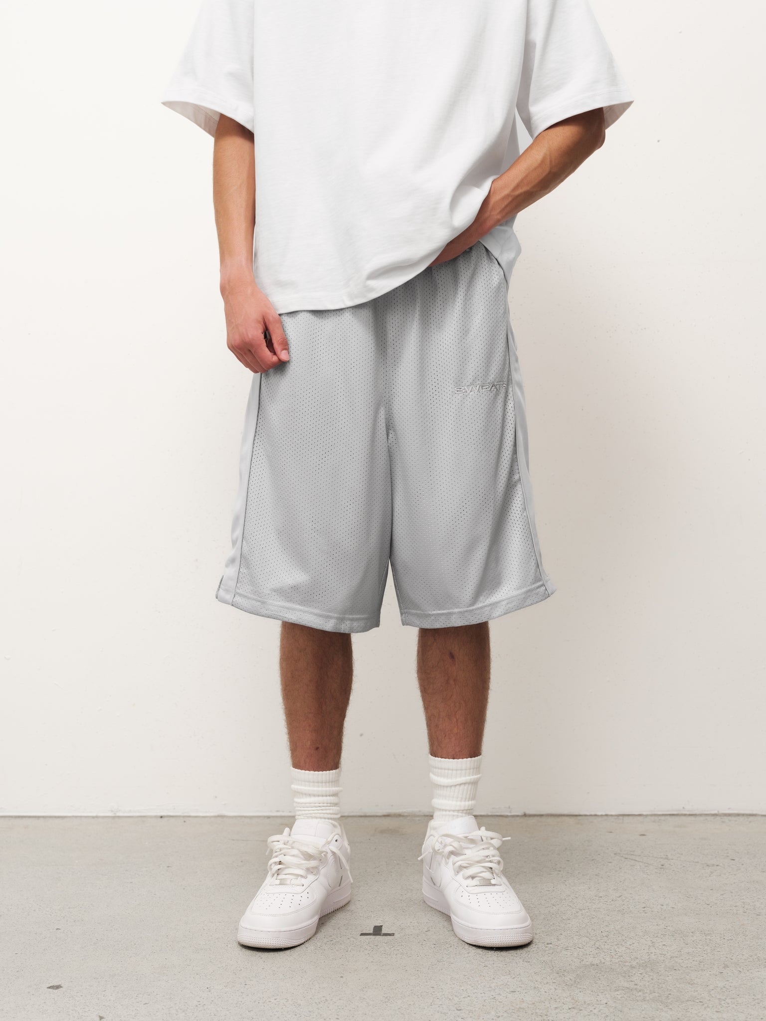 Grey mesh shorts from SWEATS EU displayed on a model in a casual setting.