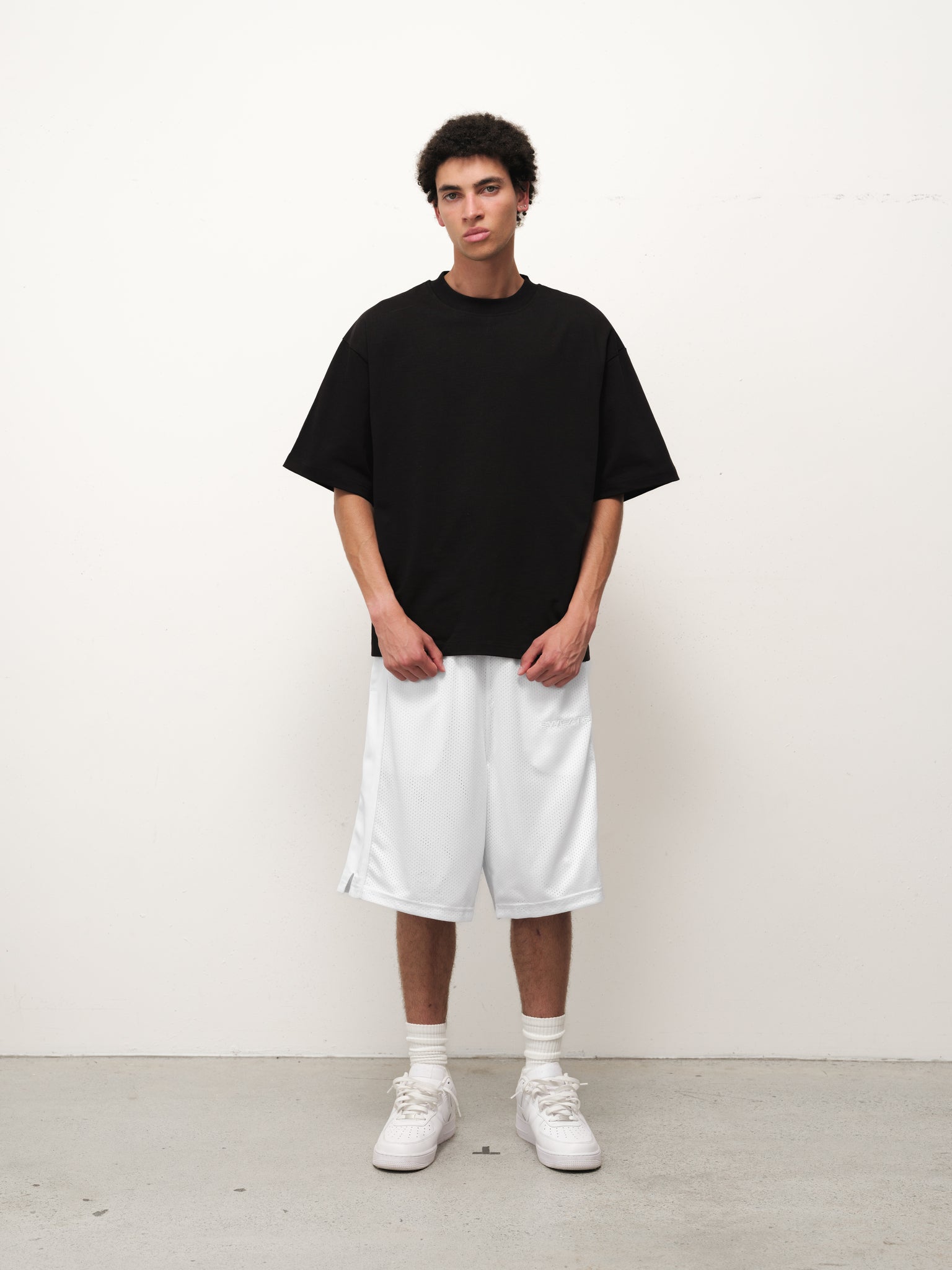 White mesh shorts from SWEATS EU displayed on a neutral background, showcasing their breathable fabric and relaxed fit.