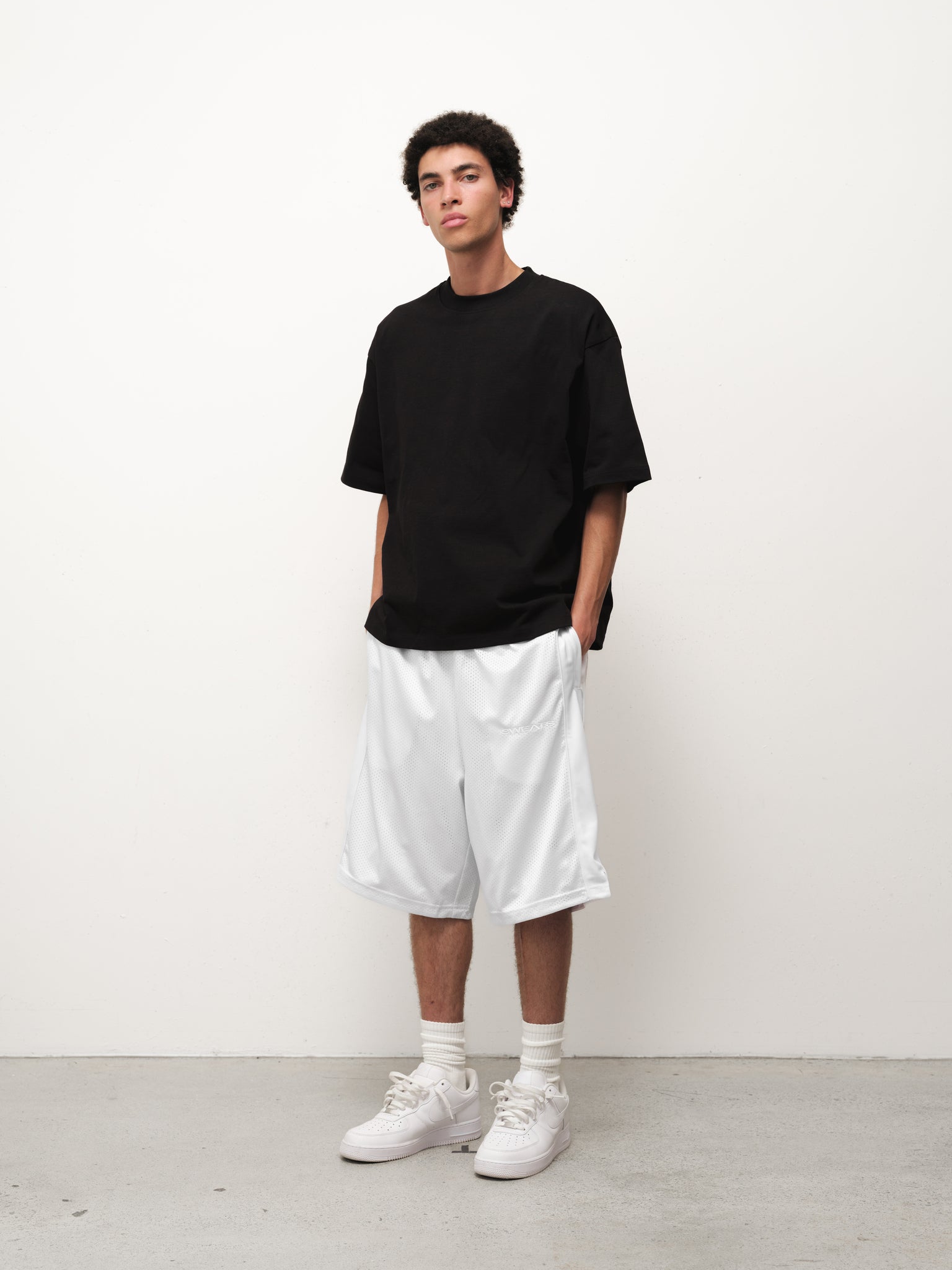 White mesh shorts from SWEATS EU displayed on a flat surface, showcasing the breathable fabric and relaxed fit.