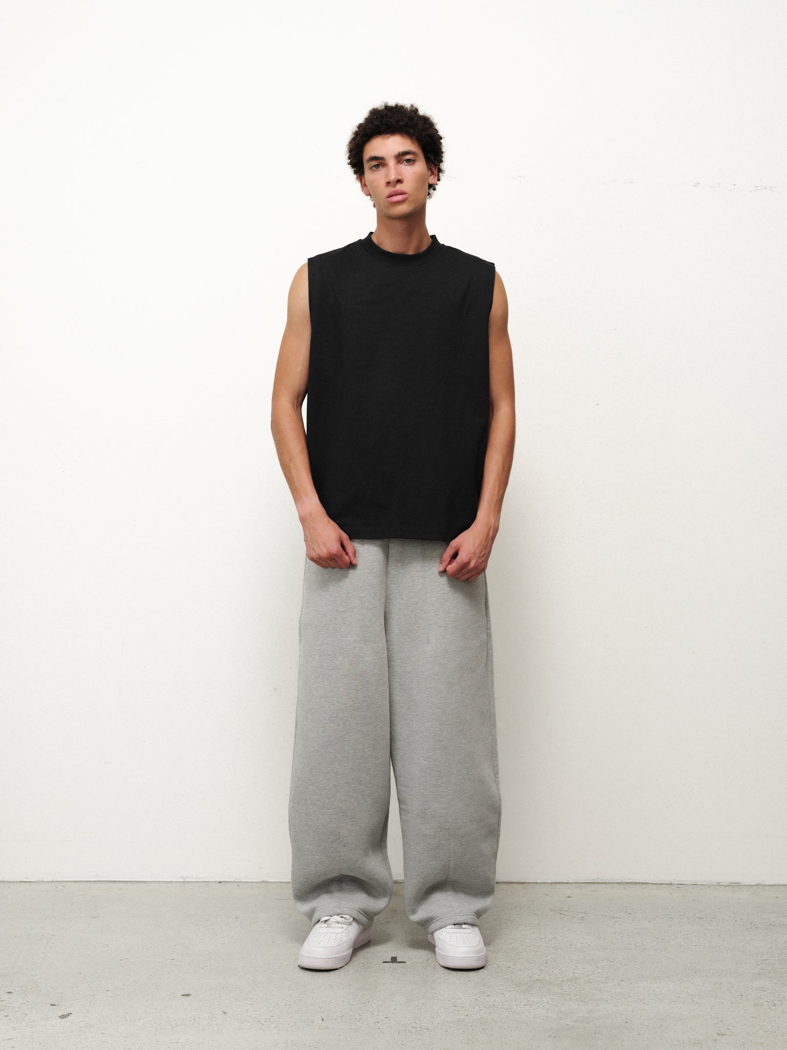 Black muscle tee from SWEATS EU, displayed flat with front view showing sleeveless design and relaxed fit.