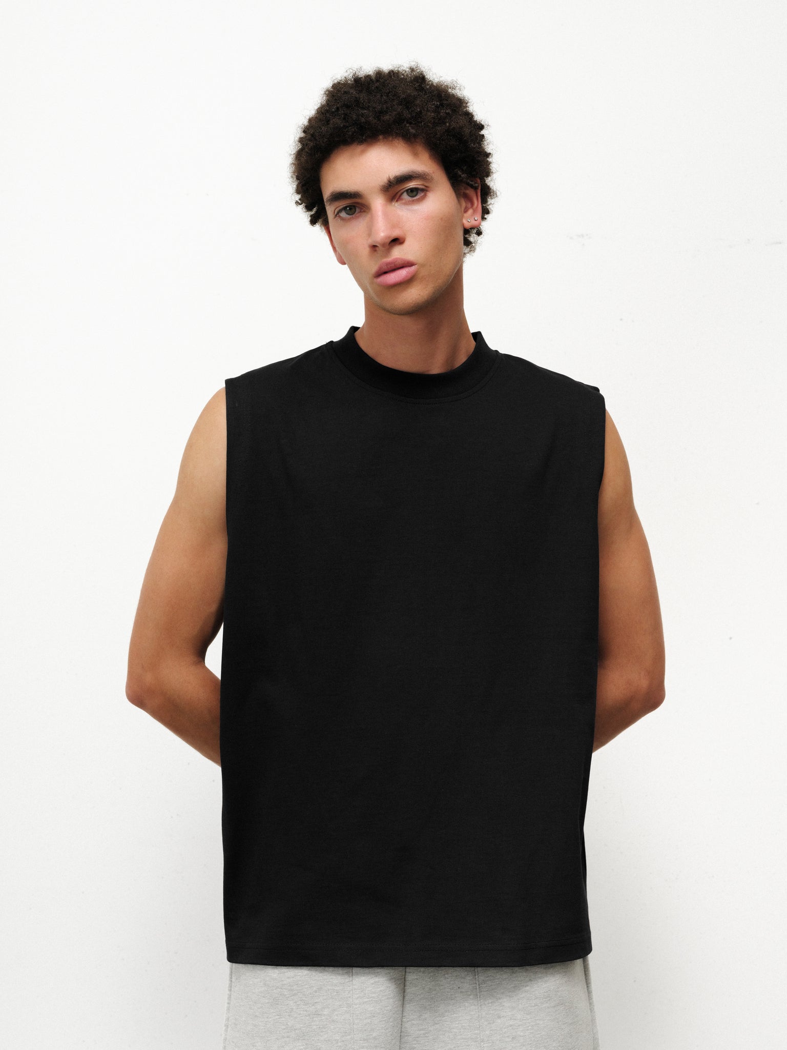Black muscle tee by SWEATS EU displayed on a model, featuring a fitted sleeveless design for activewear or casual style.