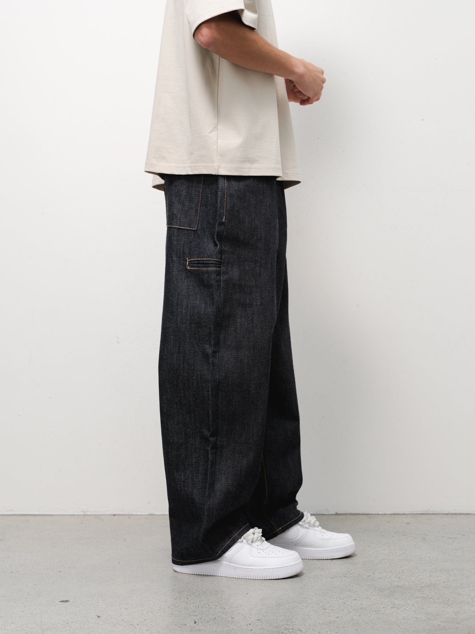 Pair of indigo denim baggy jeans from SWEATS EU shown in a full-length fashion shoot.