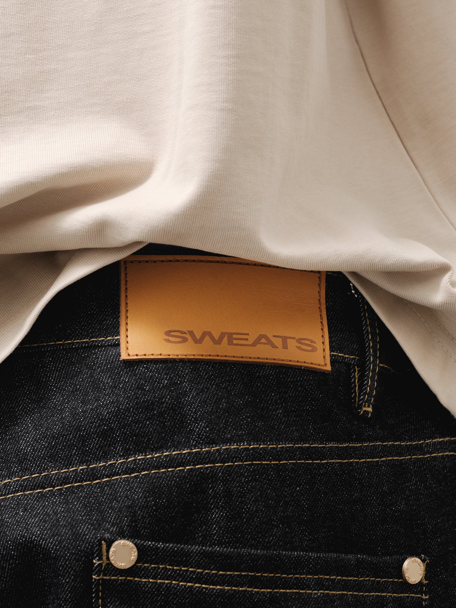 Pair of indigo denim baggy jeans from SWEATS EU, displayed hanging with a relaxed fit and classic five-pocket design.