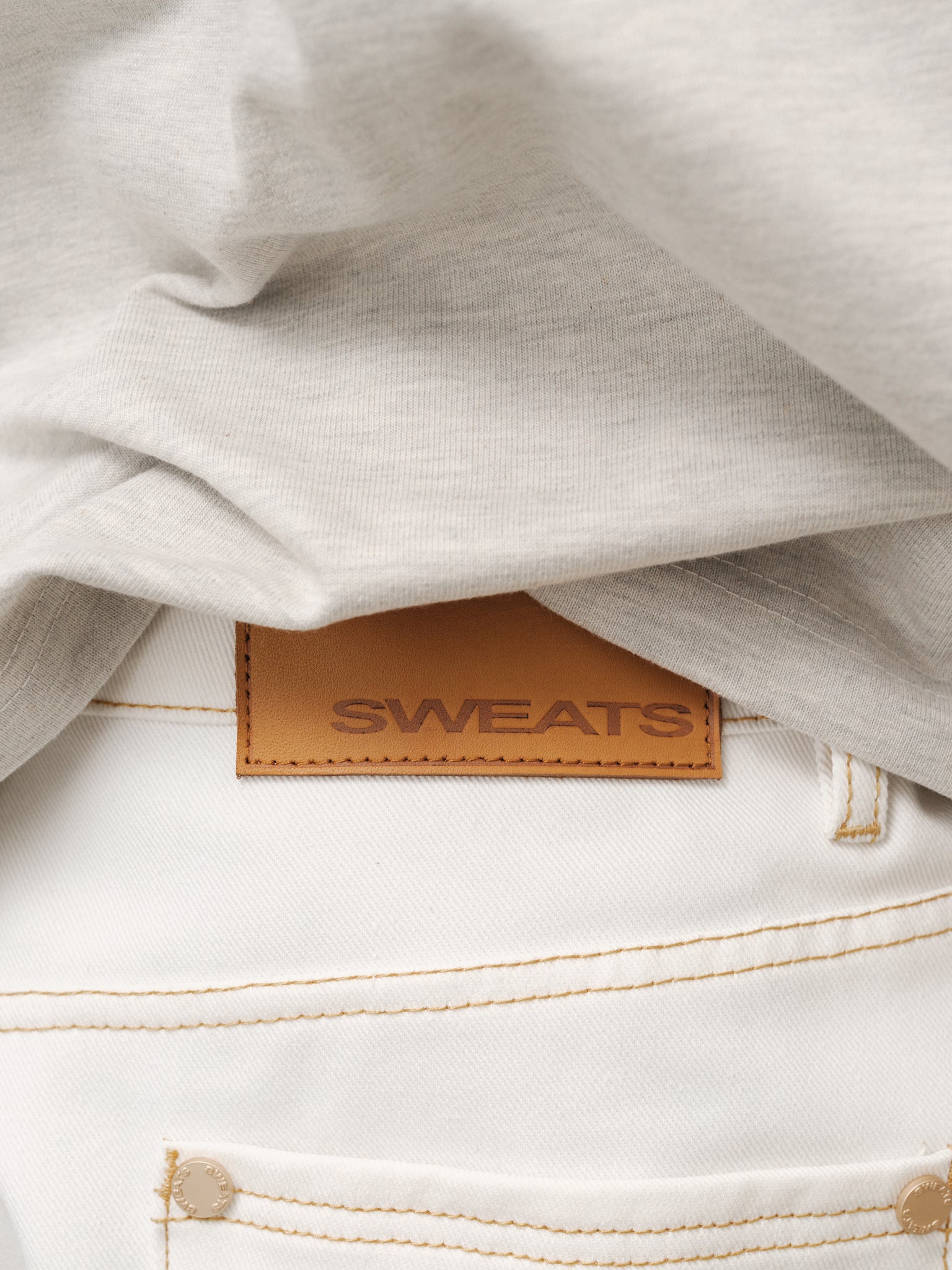 White denim baggy jeans from SWEATS EU, showing a relaxed fit with distressed details and classic five-pocket styling.