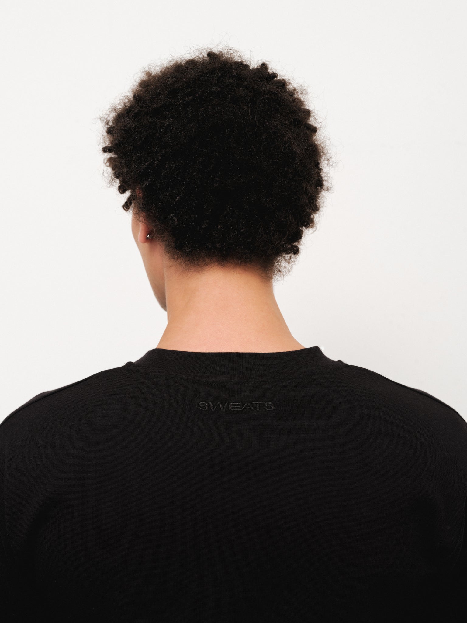 Black fitted T-shirt by SWEATS EU displayed on a neutral background, showcasing its snug fit and clean design.